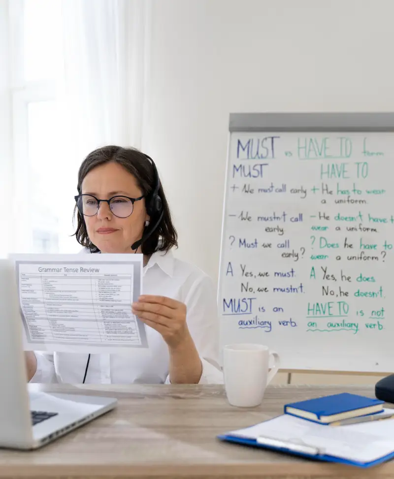 A woman wearing headphones sits at a desk, focused on her laptop while working or studying.